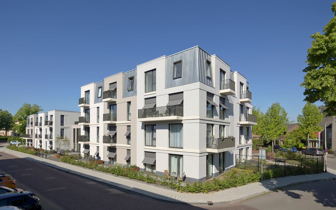 Licht appartementencomplex met balkons en groene voortuinen