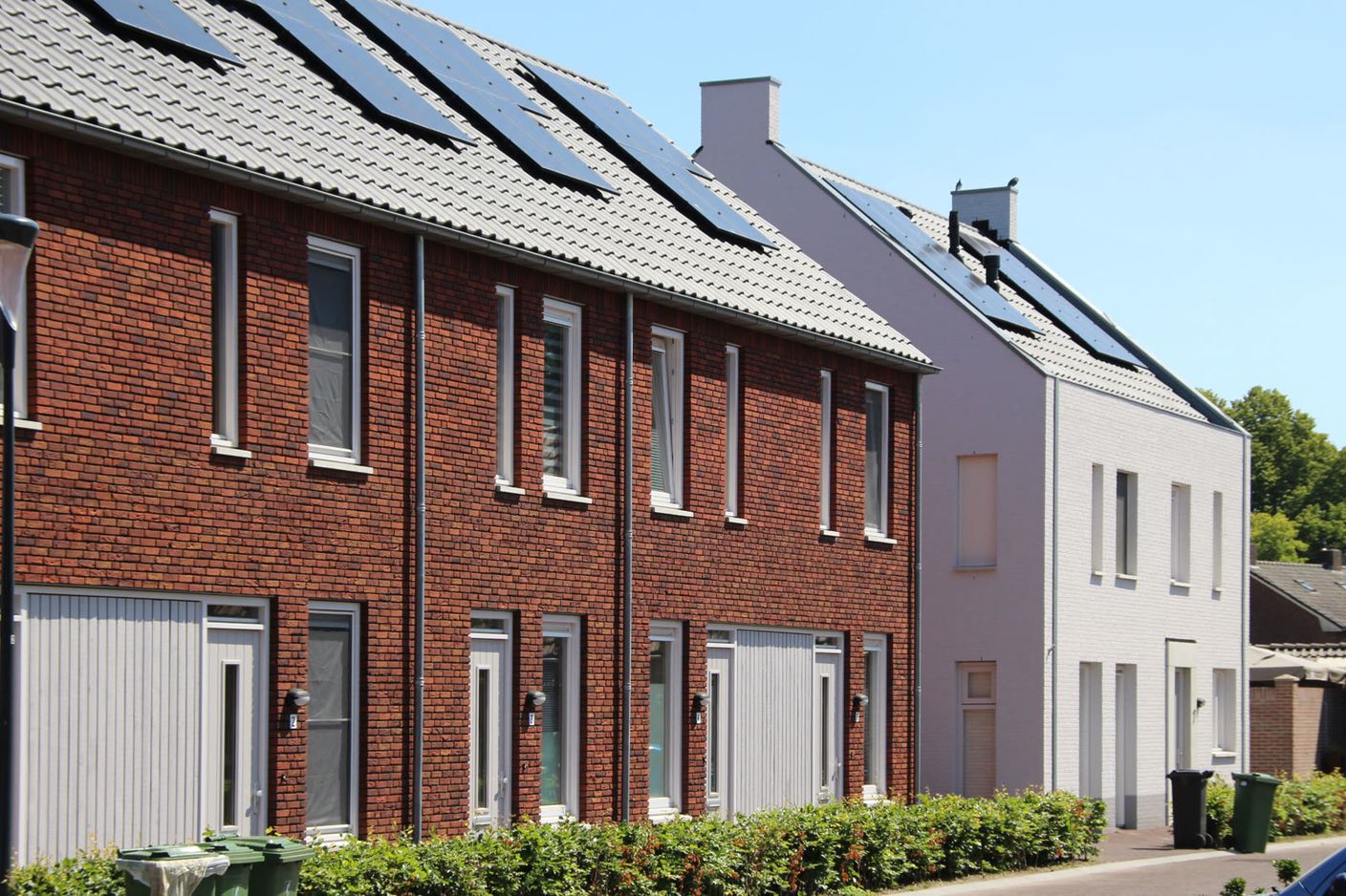 Rij nieuwe eengezinswoningen van rode baksteen met zonnepanelen